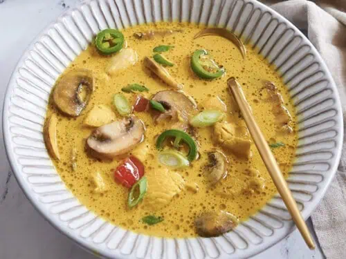 slow cooker thai curry soup in a bowl with a spoon.